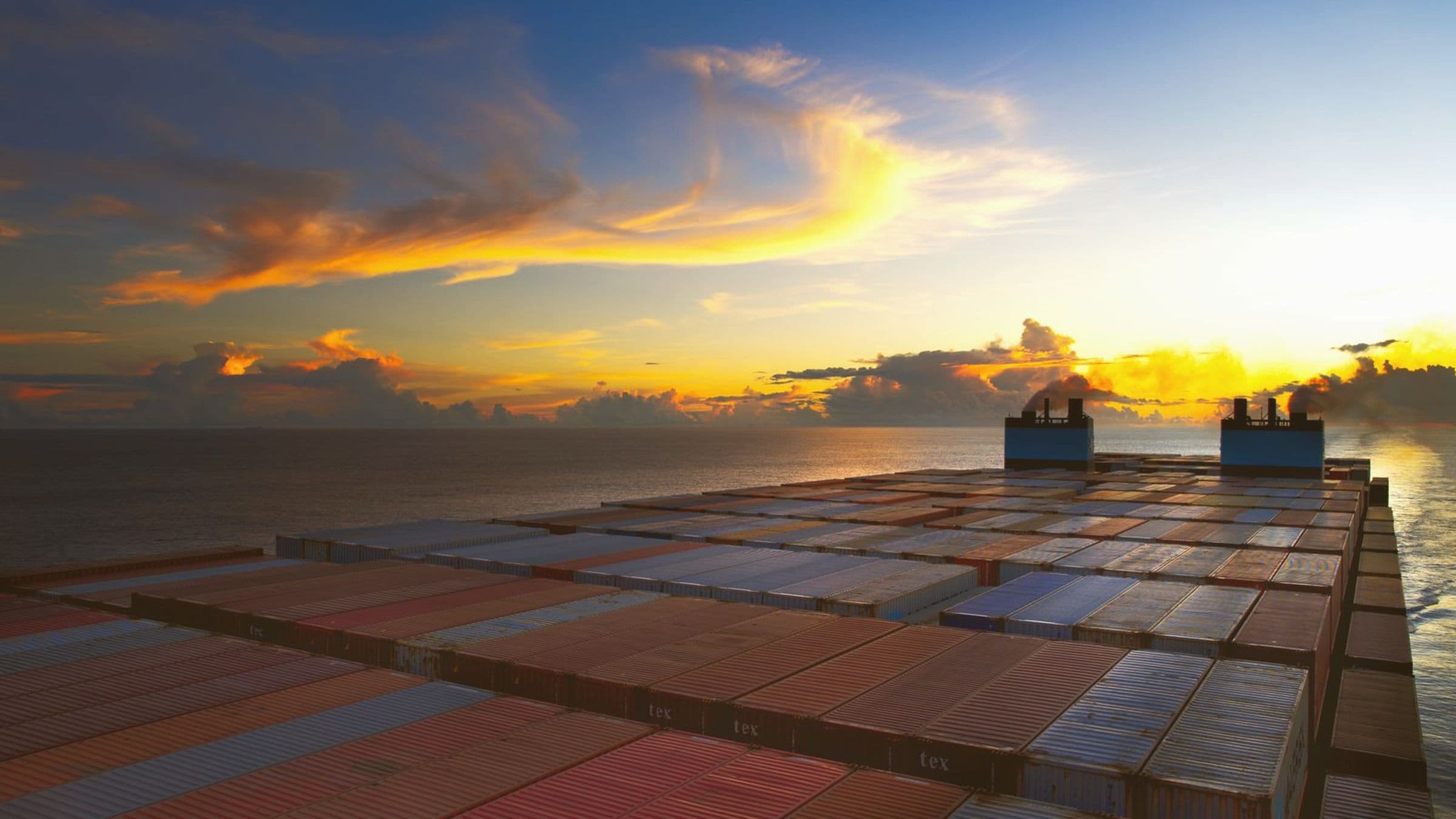 Deck of a loaded container vessel at sunset